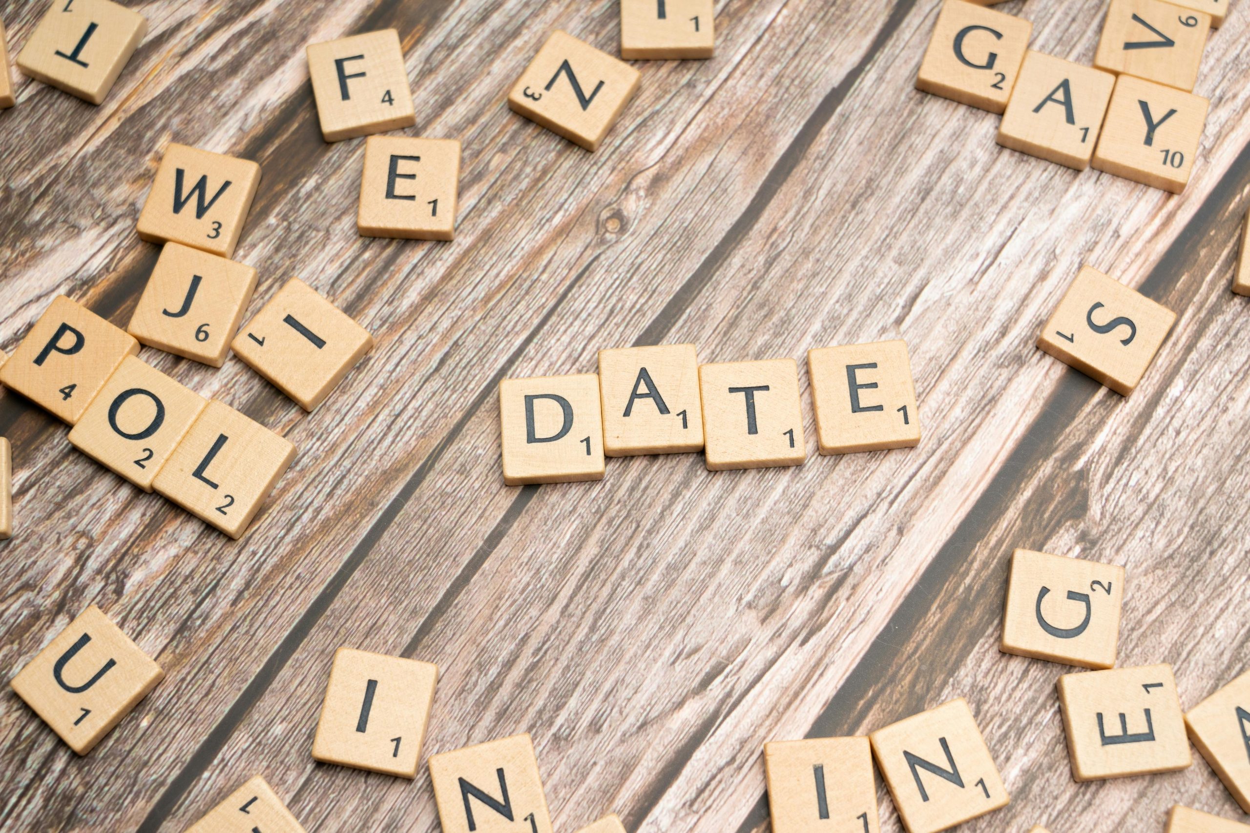 Scrabble tiles on wood spelling 'Date', creating a playful and creative scene.